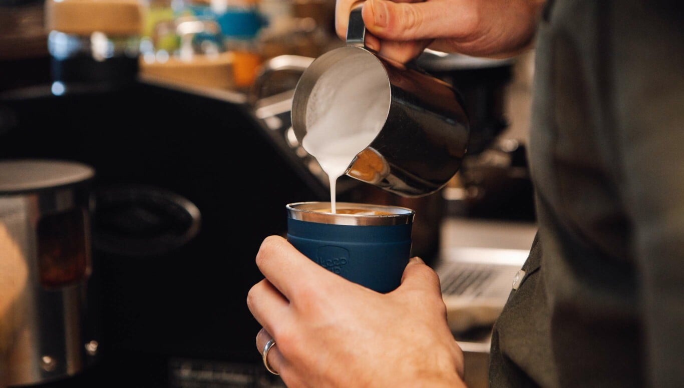 Barista pouring frothed milk into coffee in KeepCup Thermal