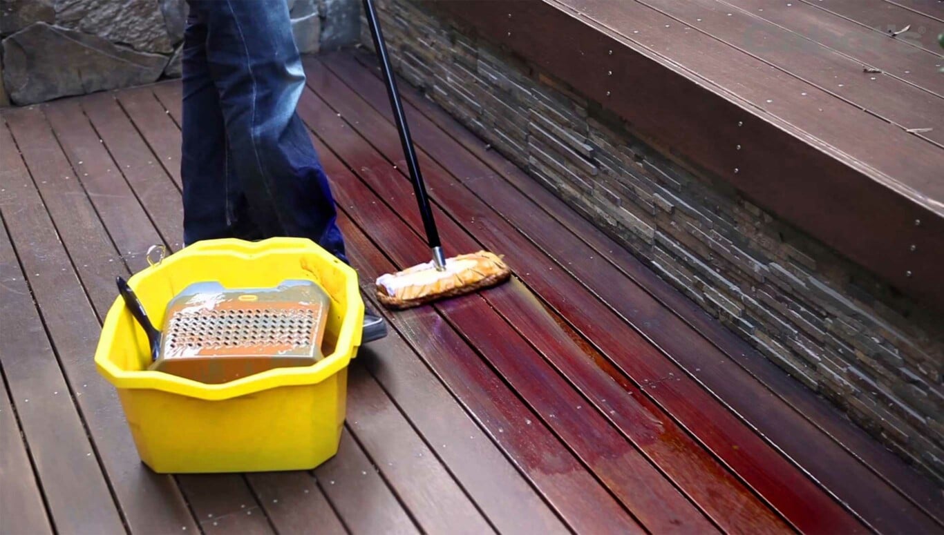 Person using Cabots DeckCoat applying oil stain onto their outdoor deck.