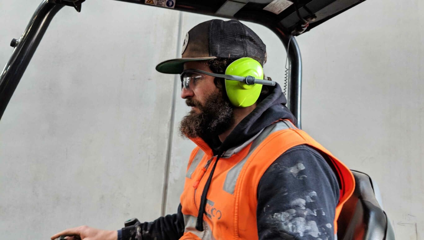 Man at worksite operating a forklift and wearing EyeSonic.